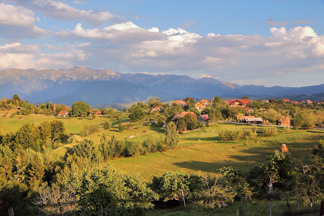 Evening sun over green hills beneath mountains