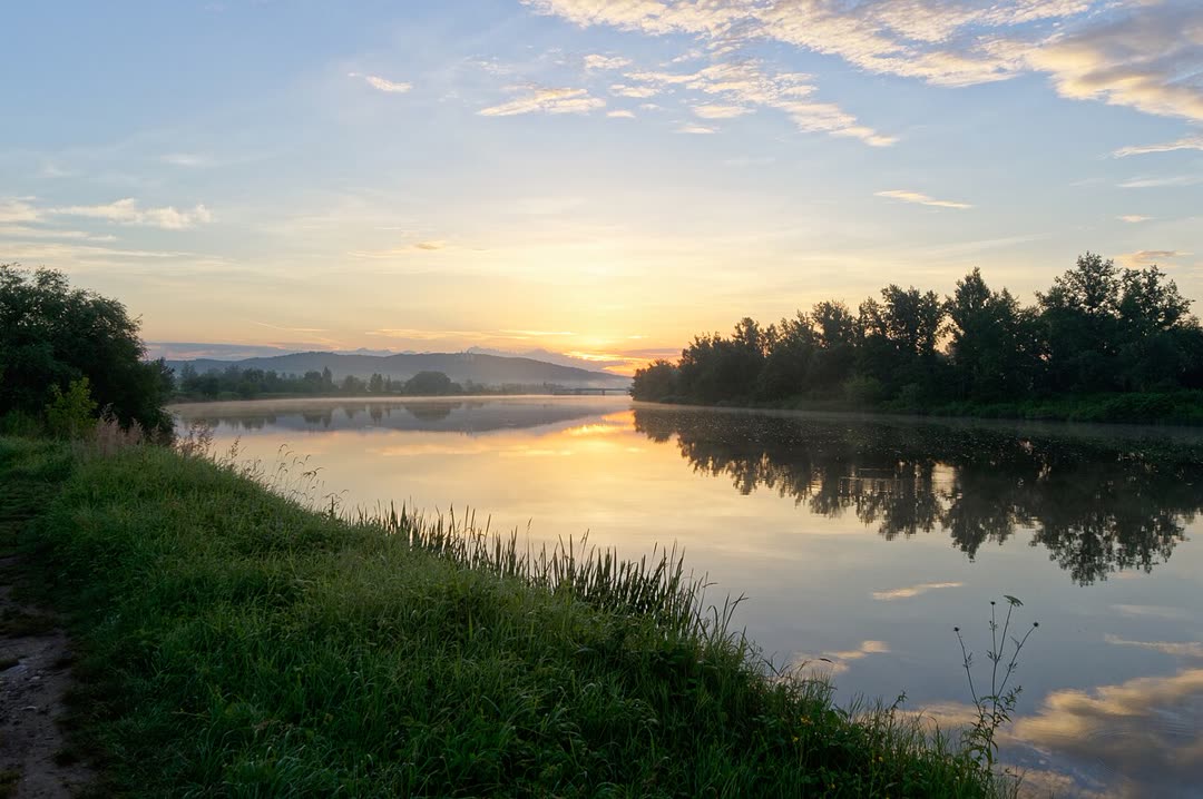 Dawn light rising over a calm river