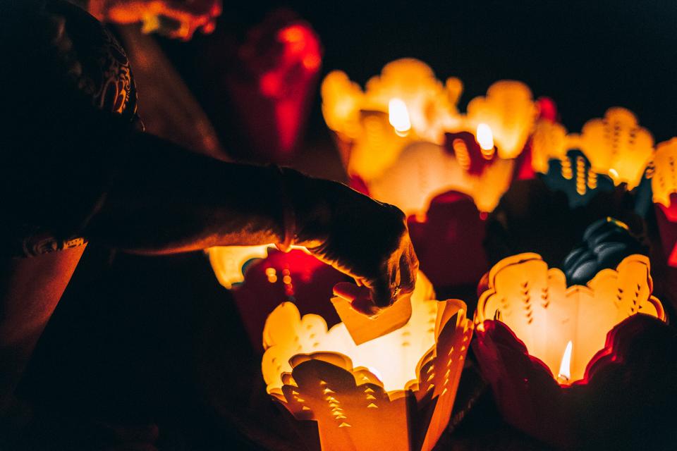 Hands lighting candle lanterns in the dark